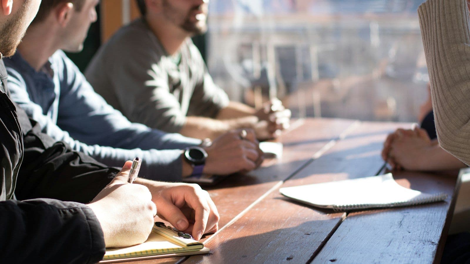 People around a table taking notes during a meeting.